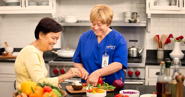 Caregiver preparing healthy food for senior woman