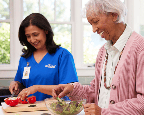 Professional caregiver helping senior woman at Thanksgiving dinner table with family in Cleveland