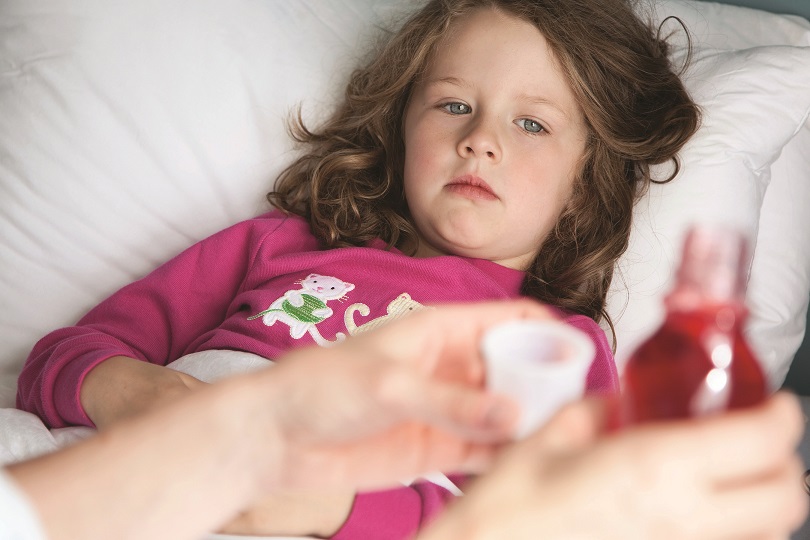 Mother giving daughter cough syrup