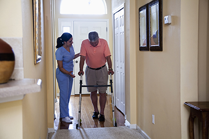 Home healthcare - Hispanic nurse at home of senior man (60s) using walker.