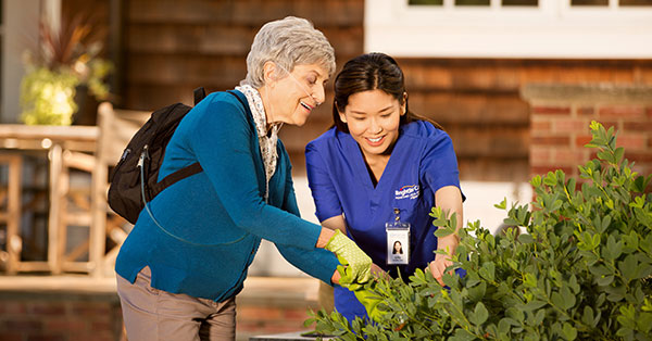 Senior Woman gardening with a Caregiver while wearing an oxygen device for supplemental air