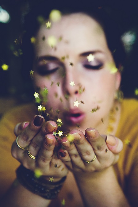 Woman blowing sparkles from hands for New Years