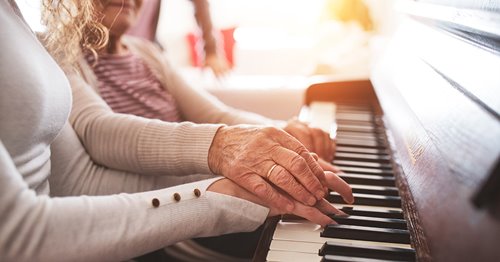 Senior with Alzheimer's playing piano with granddaughter