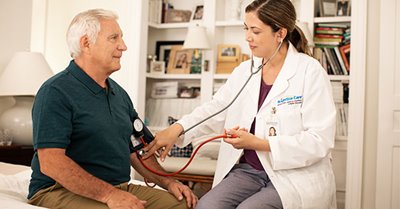 CNA taking blood pressure of senior man