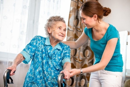 Young woman assisting elderly woman with walker