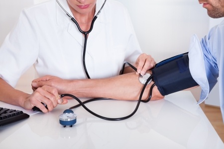 Attractive young female doctor or nurse taking a male patients blood pressure using a sphygmomanometer