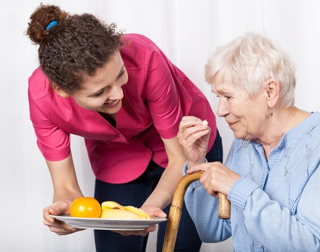 Young woman serves elderly woman a meal